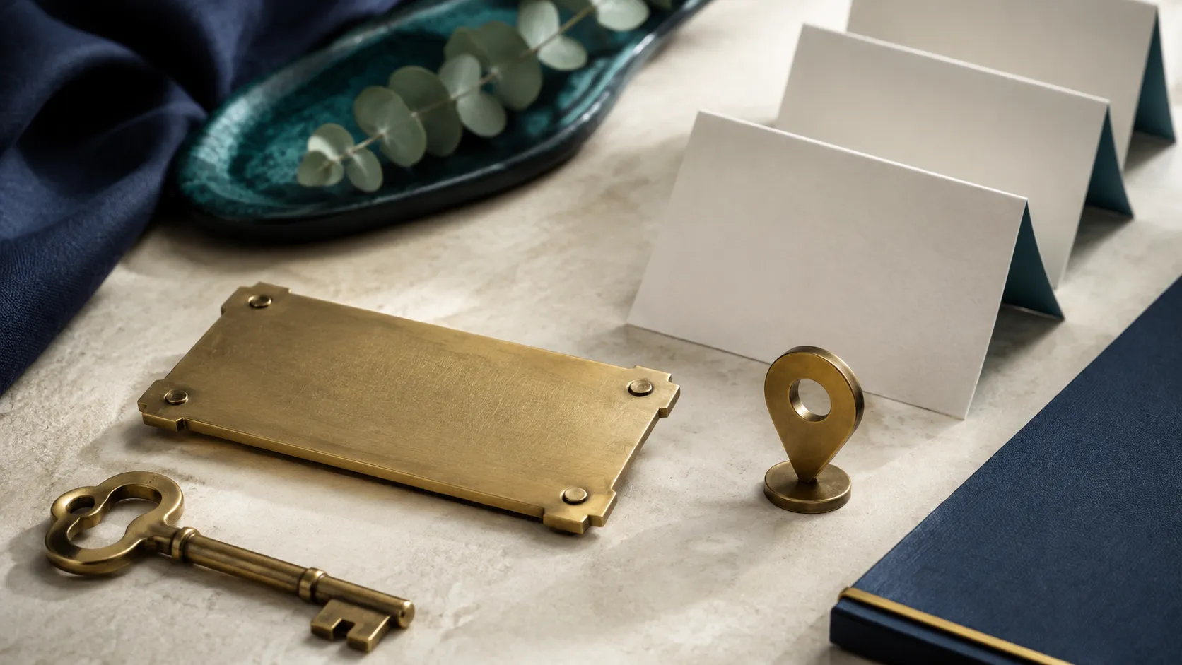 An unbranded storefront key, location pin, and matching blank cards arranged on a stone surface.