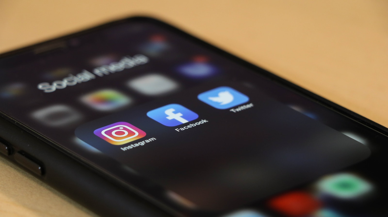 Close-up of a phone showing Facebook, Instagram, and other social media apps.