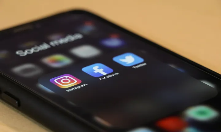 Close-up of a phone showing Facebook, Instagram, and other social media apps.