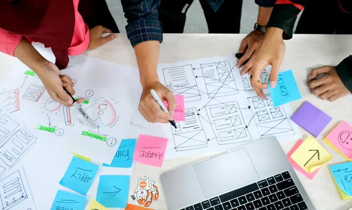 Marketing planning workshop with a team reviewing strategy notes around a table.