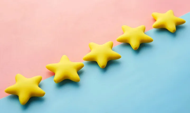 Close-up of a five-star review rating on a mobile phone.