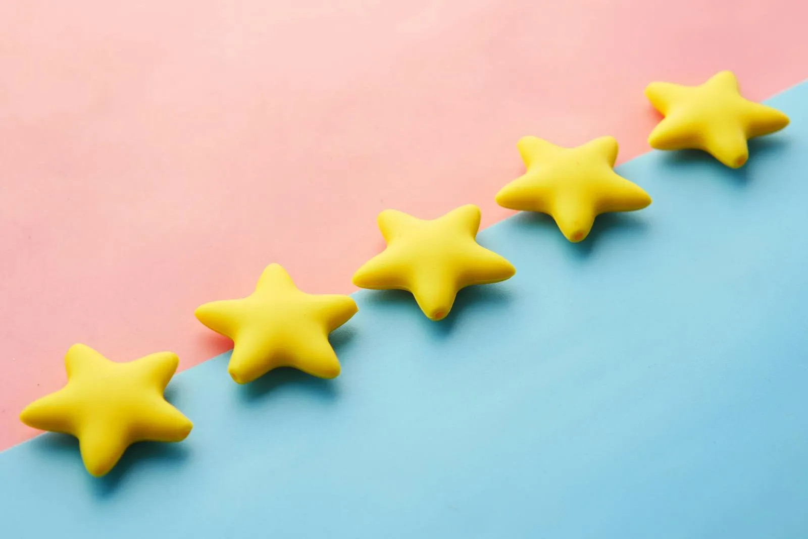 Five yellow review stars arranged diagonally on a pink and blue background