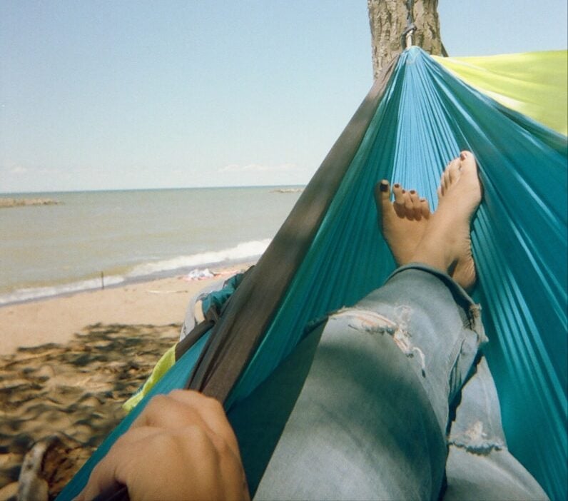 a person laying in a hammock on the beach